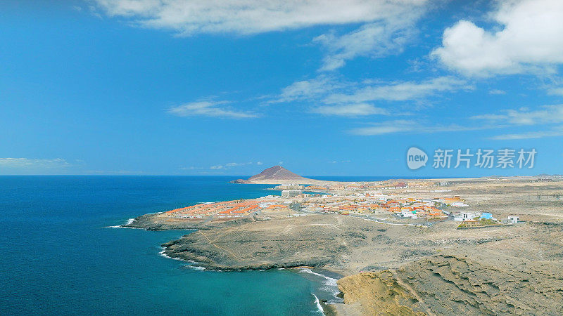 Aerial view of the coast in the natural reserve of "Montaña Pelada" and town of El Medano in the background. Tenerife, Canary Islands. Drone shot